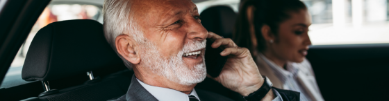 Senior manager sitting in car on phone with field sales rep in passenger seat